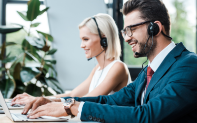 Call Centers versus Omni-Channel Contact Centers. What is the difference? Happy man wearing a headset and working on laptop with female coworker doing the same in background