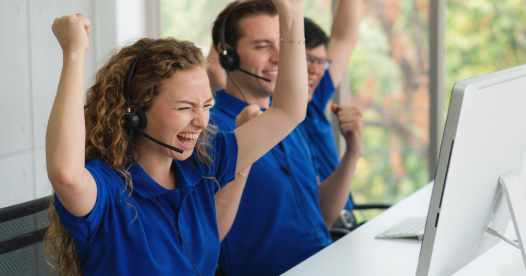 3 Ways to Motivate Contact Center Agents - female agent celebrating a win with coworkers next to her