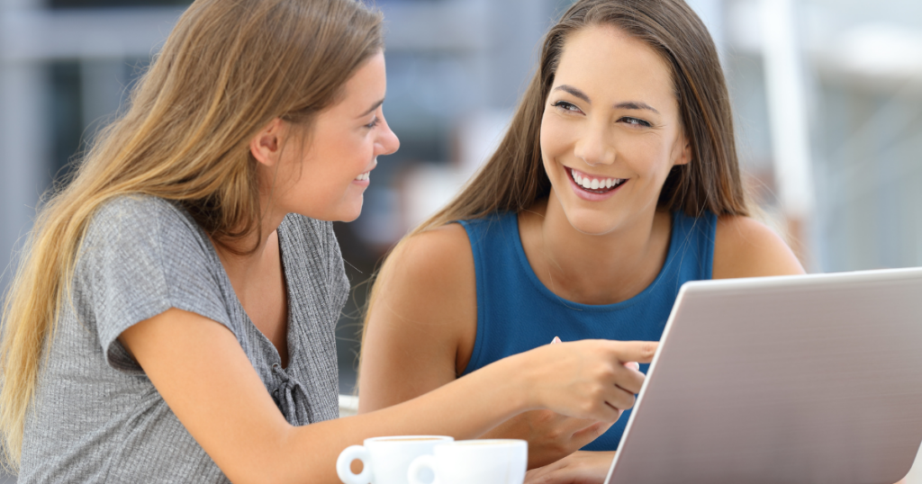 What are the 10 Principles of Customer Service? - two happy women discussing something they're looking at on a laptop