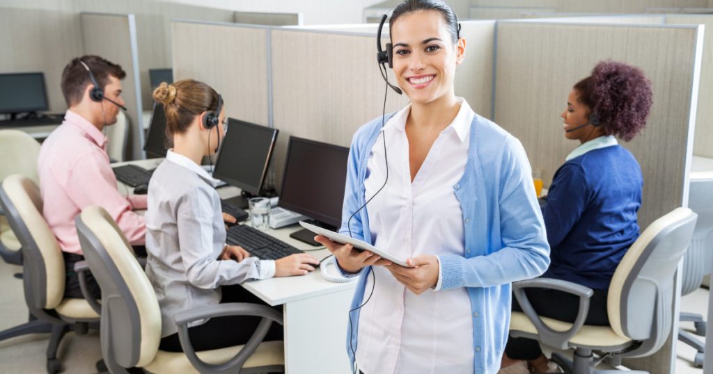 Inside the Contact Center: 5 Secrets Behind a Stellar Customer Experience Program - contact center agent with tablet in front of others at desks