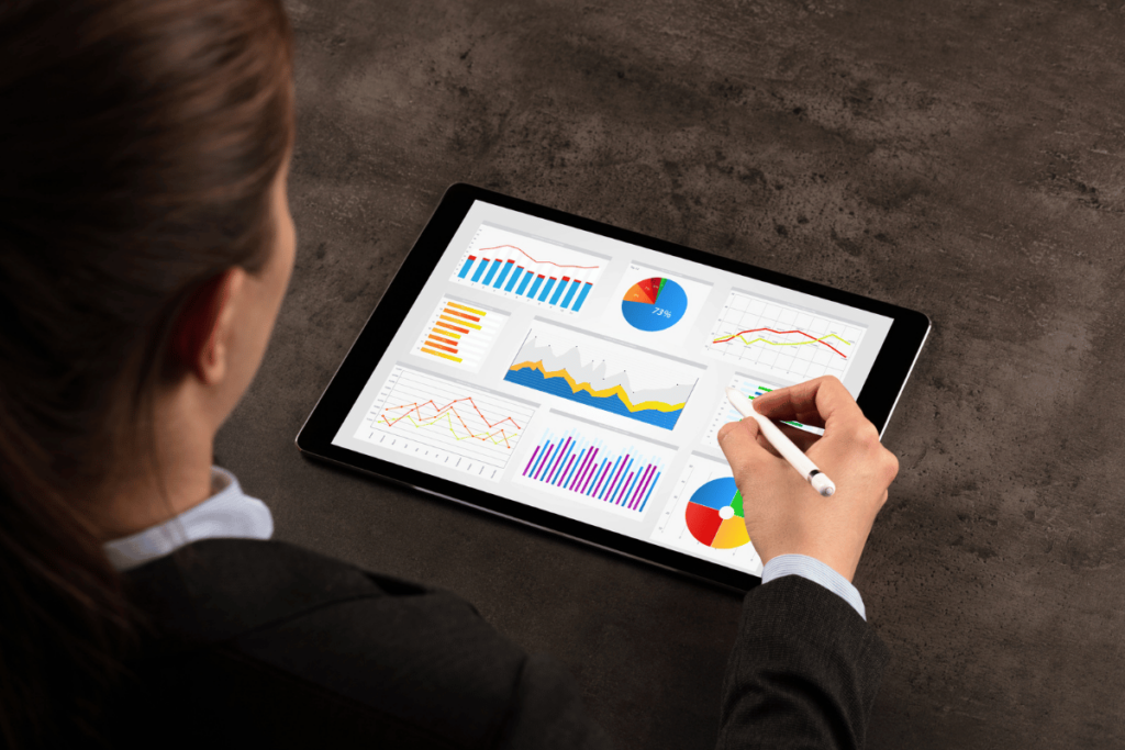 How To Improve Your Contact Center Performance Using Analytics. An elegant businesswoman looks at a tablet with colorful graphs and charts.