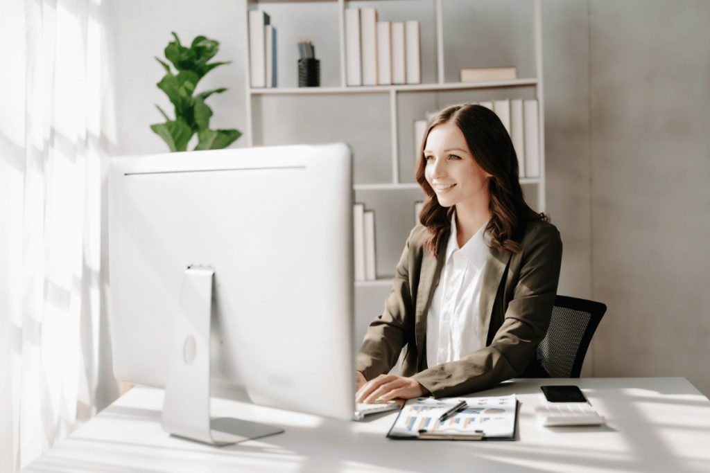 Thanks to AI, Now You Can Automate Quality Assurance. A smiling businesswoman works at her computer in her office.