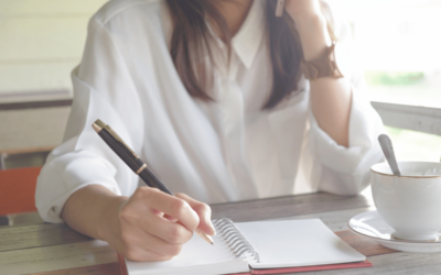 Business woman on phone while holding pen to take notes in a notebook.