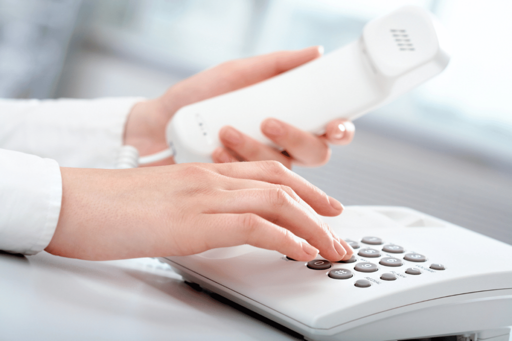 closeup of woman's hands holding the telephone receiver as she pushes the phone buttons