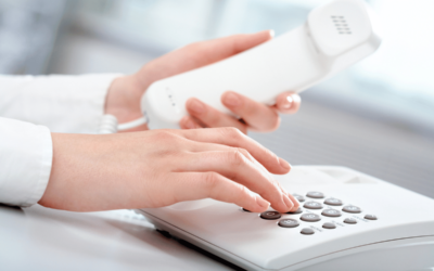 closeup of woman's hands holding the telephone receiver as she pushes the phone buttons